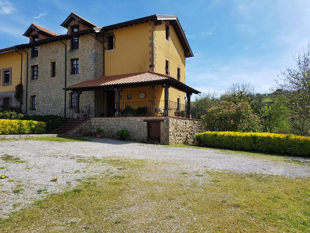 una gran casa amarilla con una entrada delante de ella en El Pedroso, en Santillana del Mar