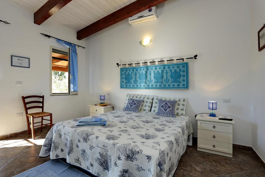 1 dormitorio con 1 cama con colcha azul y blanca en B&B Nonno Stacca, en Stintino