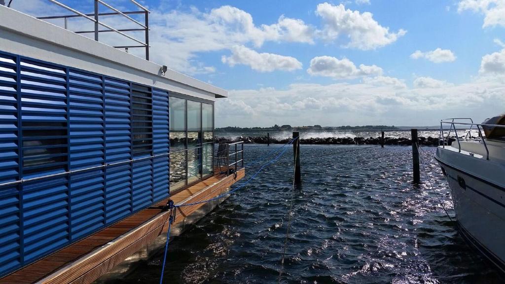 a boat in the water next to a building at Hausboot FJORDBLIK in Kollund Østerskov