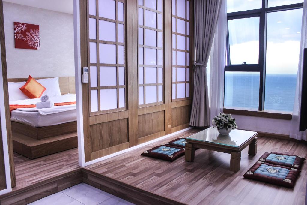 a room with a bed and a table and windows at Gold Ocean Apartment in Nha Trang