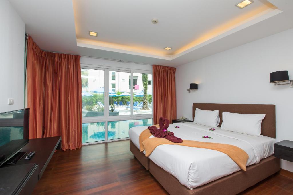 The Palms, Kamala Beach - SHA Extra Plus في شاطئ كامالا: غرفة نوم بسرير كبير ونافذة كبيرة