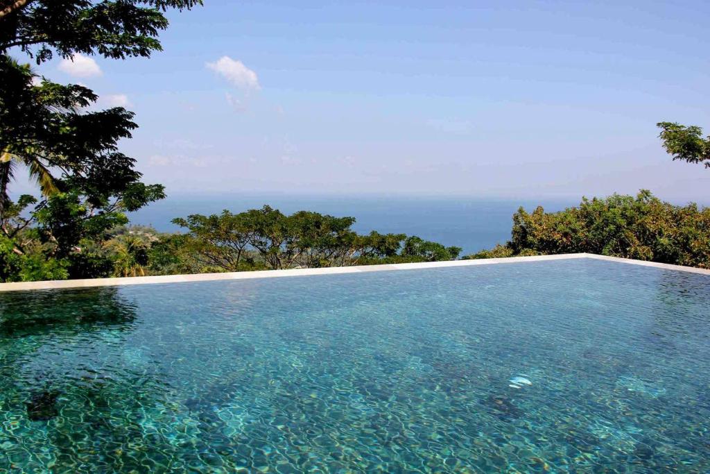 uma piscina com o oceano ao fundo em Villa Vanna - Lombok em Senggigi