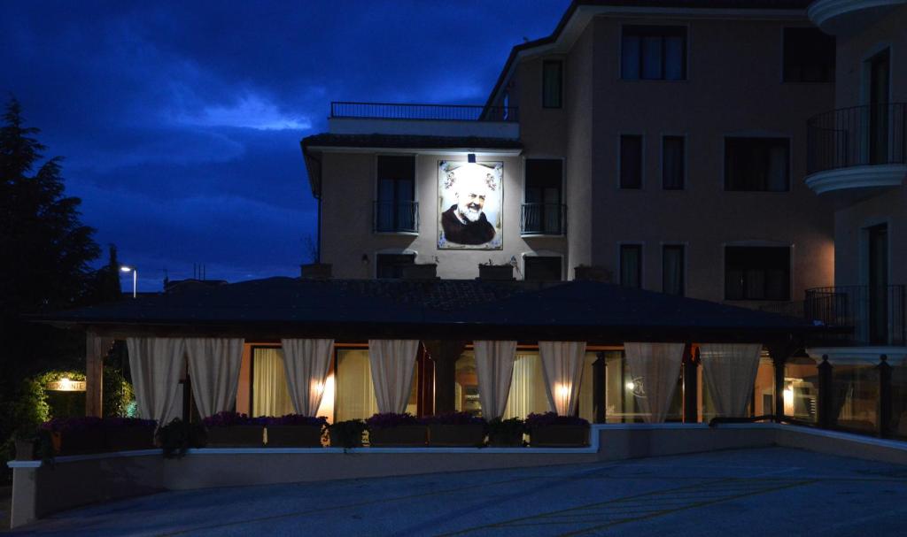 a building with a clock on the side of it at night at Hotel Rosamarina in San Giovanni Rotondo