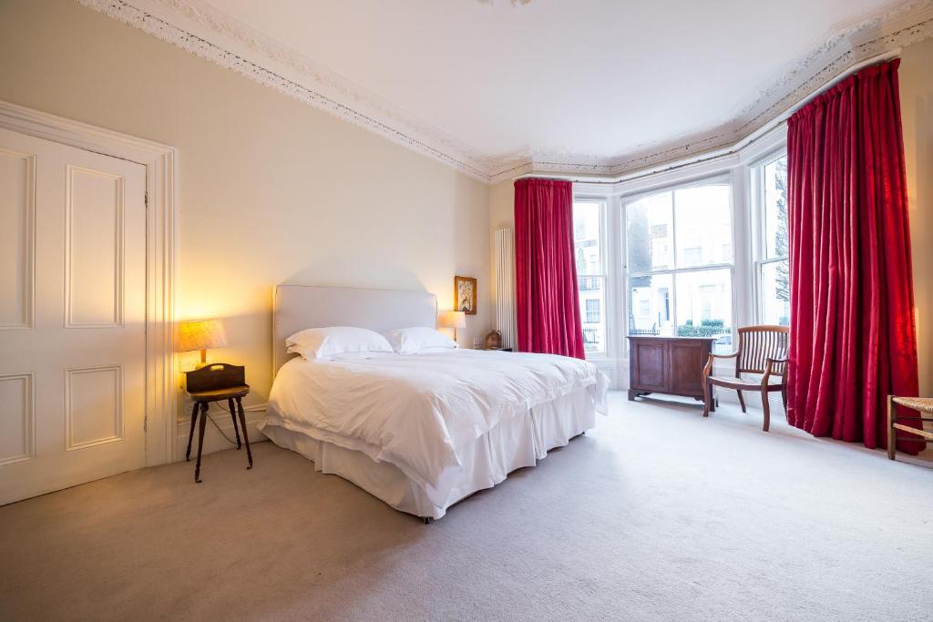 倫敦的住宿－The Bockery Suite 1 Chelsea，一间卧室配有一张带红色窗帘的大床