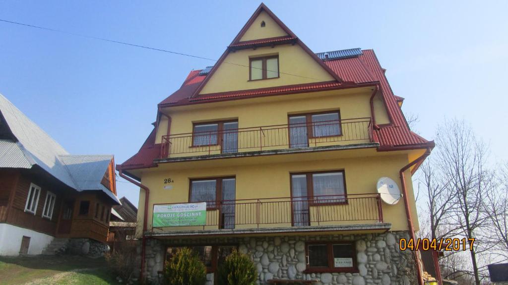 ビャウカにあるAgroturystyka Zdzisława i Kazimierz Remiaszの赤い屋根の高い黄色の建物