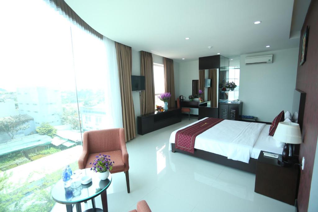 una camera con letto, sedia e tavolo di Huong Son Hotel Da Nang a Da Nang