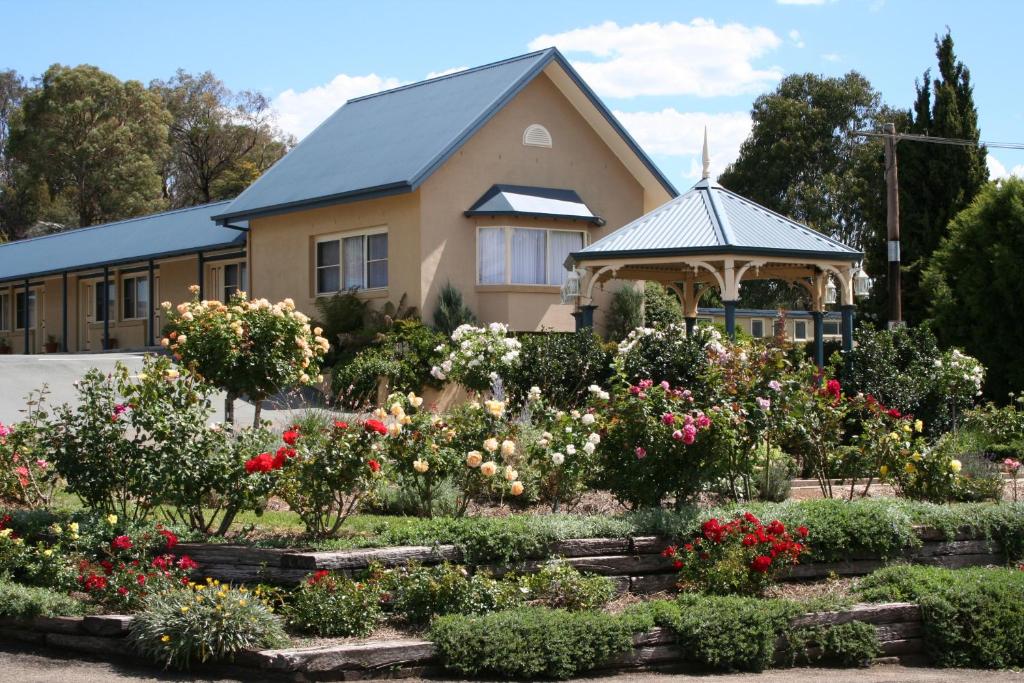 a house with a garden of flowers in front of it at Willows Motel in Goulburn
