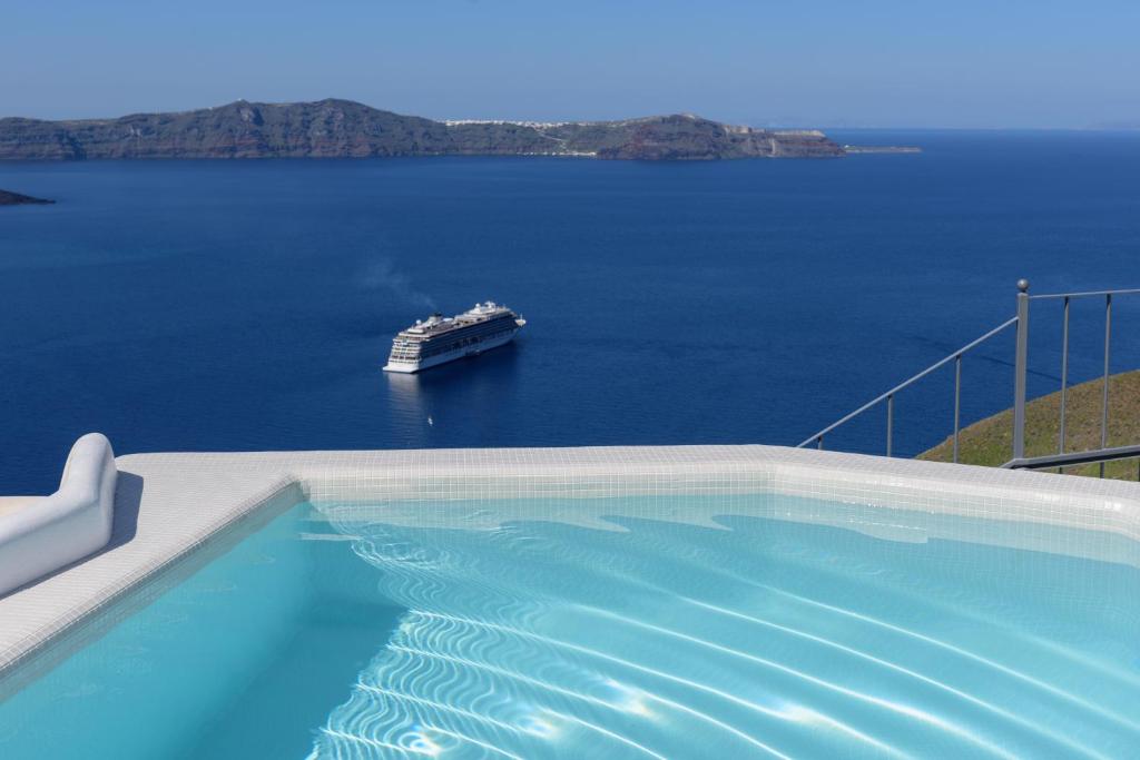 a large swimming pool with a cruise ship in the water at Villa Renos Hotel in Fira