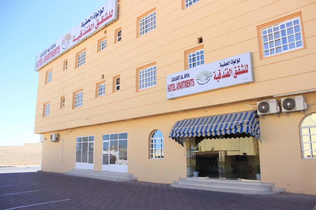 a building with a sign on the side of it at Luluat Al Afia Hotel Apartments in Sur
