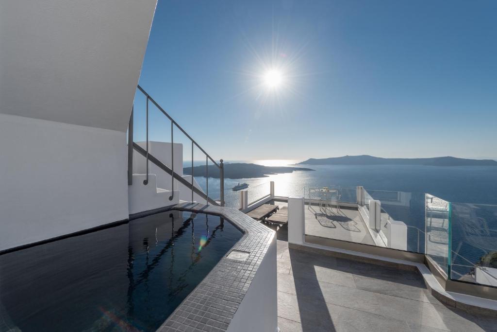a swimming pool on the balcony of a house with the ocean at Villa Renos Hotel in Fira