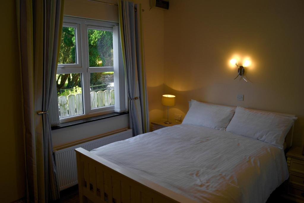1 dormitorio con cama blanca y ventana en Old School House Belcoo 41, en Belcoo
