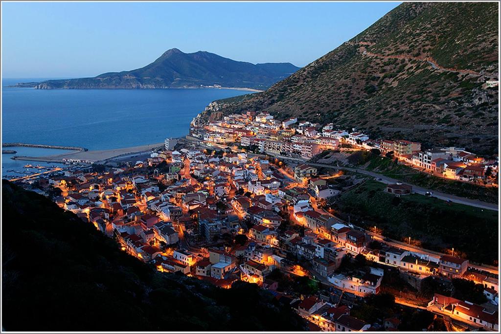 una città sul fianco di una montagna di notte di Appartamento Rosmarino a Buggerru