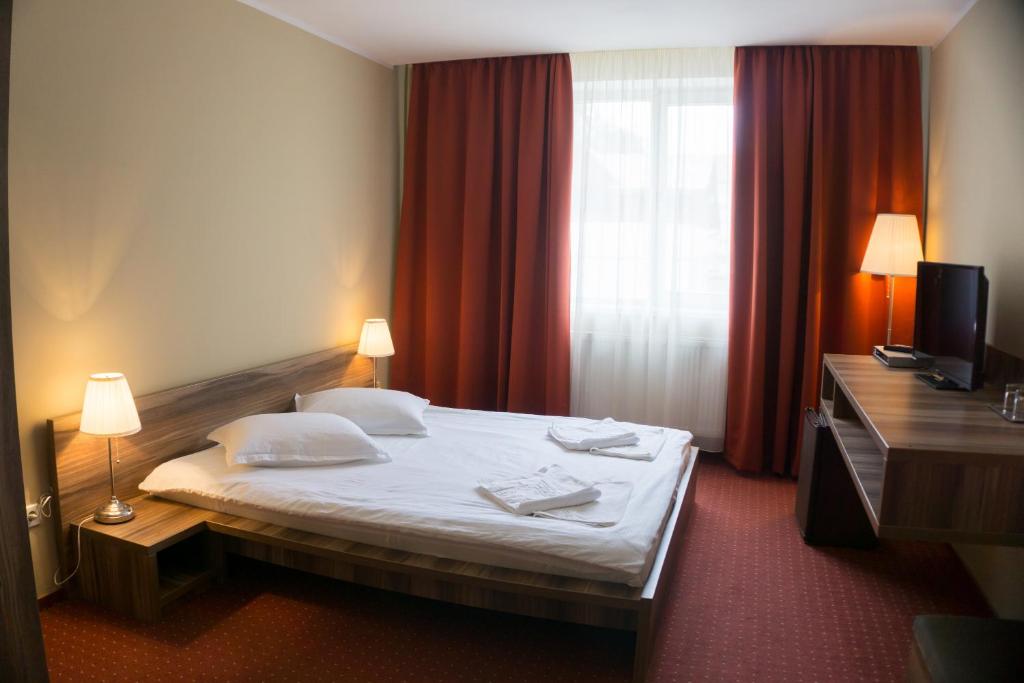 a hotel room with a bed and a window at Hotel Merkur in Miercurea-Ciuc