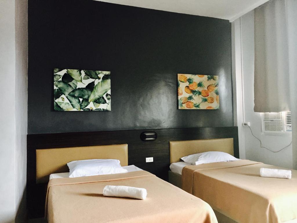 two beds in a room with paintings on the wall at LEUX Hotel in Panglao Island