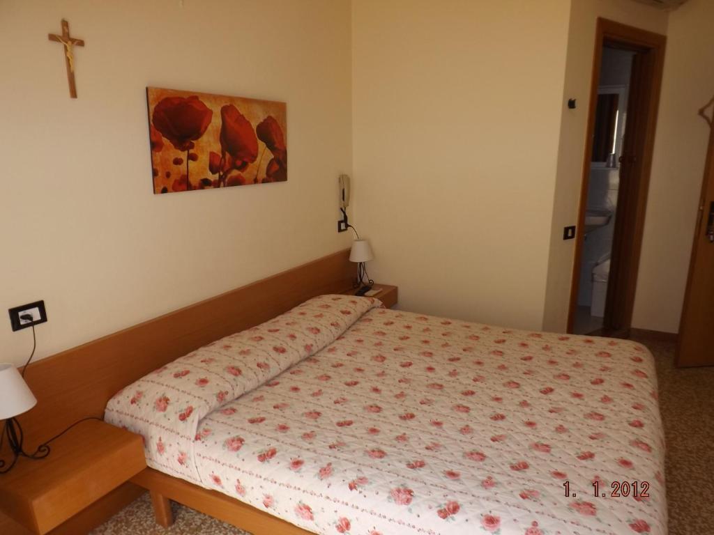 una camera da letto con un letto con una croce sul muro di Albergo Dal Baffo a Lazise
