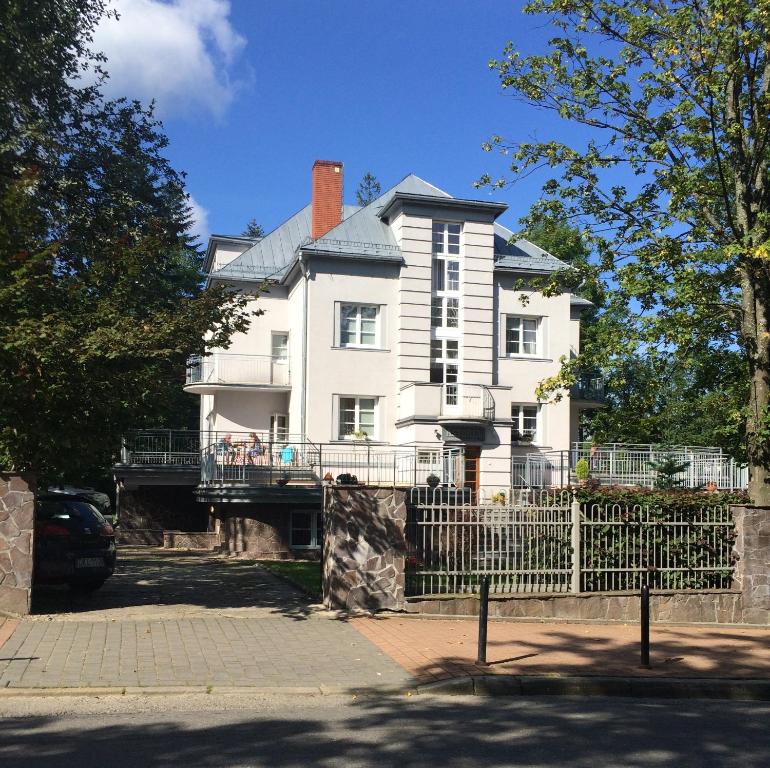 une grande maison blanche avec une clôture devant elle dans l'établissement Astoria - Willa Literatów, à Zakopane