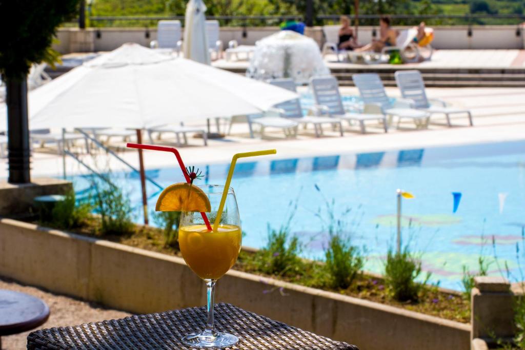 a drink sitting on a table next to a pool at Hotel Cliff Belvedere in Izola