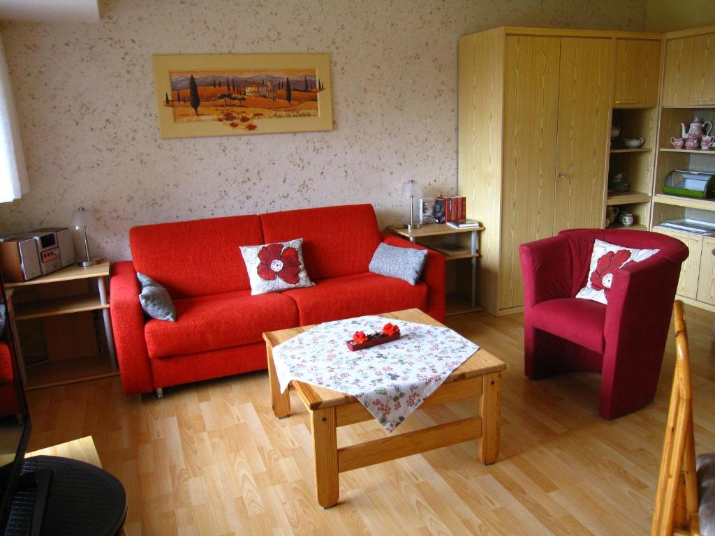 salon z czerwoną kanapą i stołem w obiekcie Ferienwohnung Kleinschmidt w mieście Heimbach