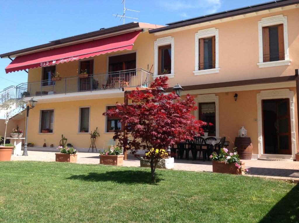 a house with a red tree in the yard at B&B Acero Rosso in San Giovanni Lupatoto