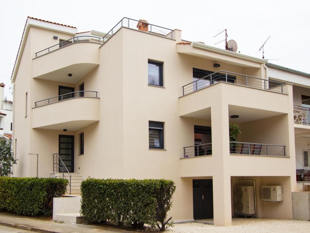 un immeuble d'appartements avec balcon et buissons dans l'établissement Apartments Adria, à Poreč