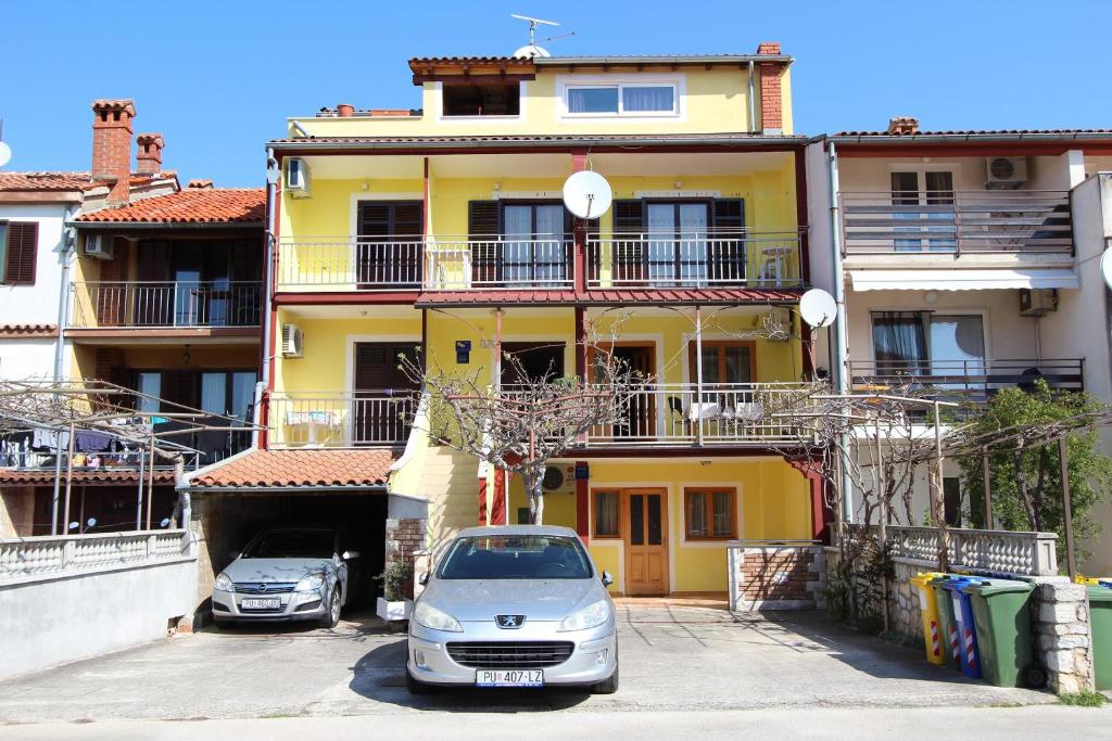 samochód zaparkowany przed żółtym budynkiem w obiekcie Room and Apartments Mariza w Rovinj