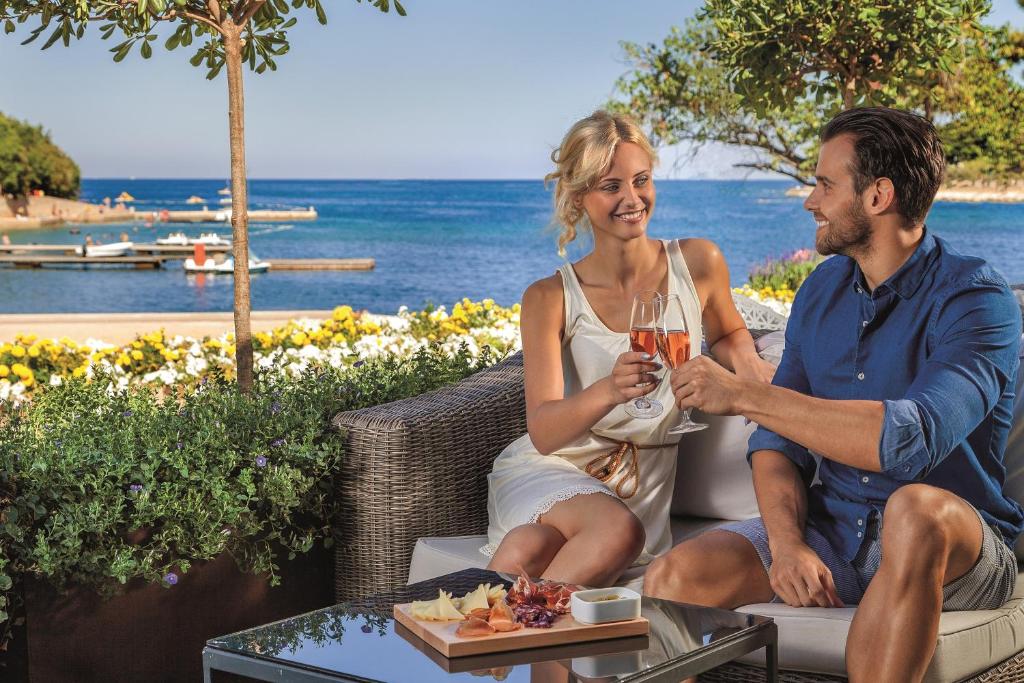 a man and a woman sitting on a table with a drink at Hotel Istra Plava Laguna in Poreč