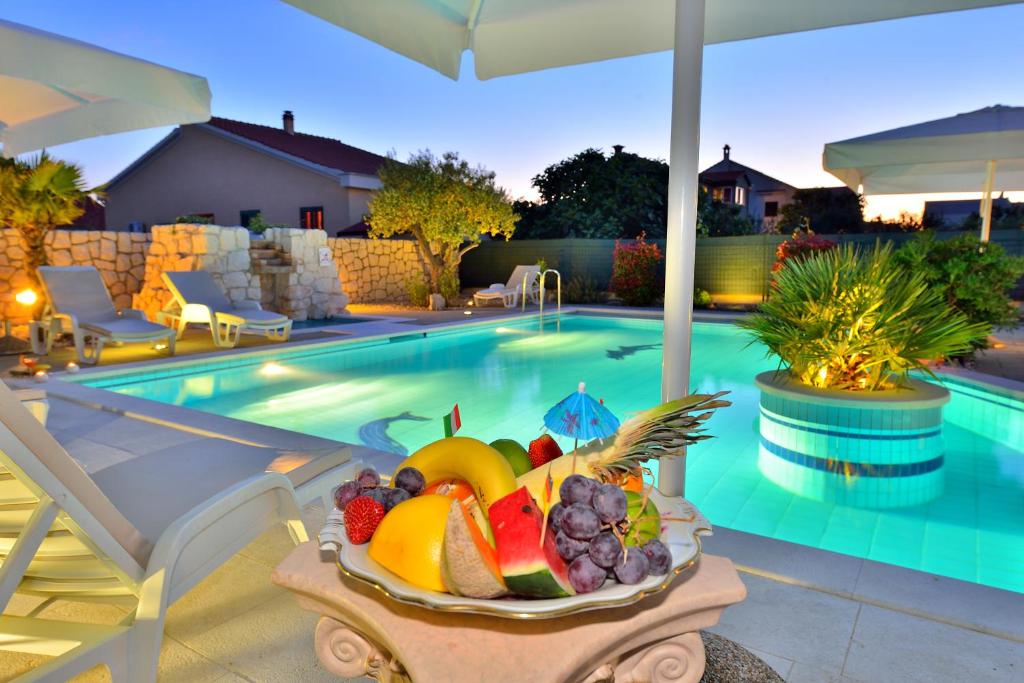 a bowl of fruit on a table next to a swimming pool at Villa Dalmatina Zadar mit Pool in Zadar