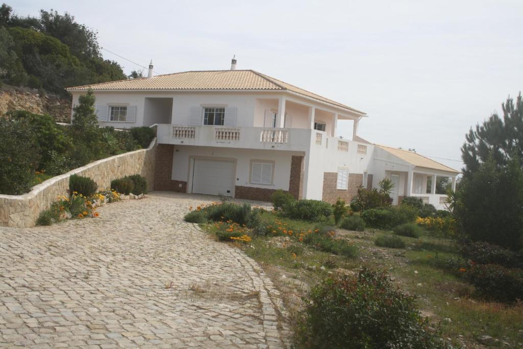 una casa blanca en una colina con una entrada de piedra en Rustic Villa Guesthouse, en Santa Bárbara de Nexe