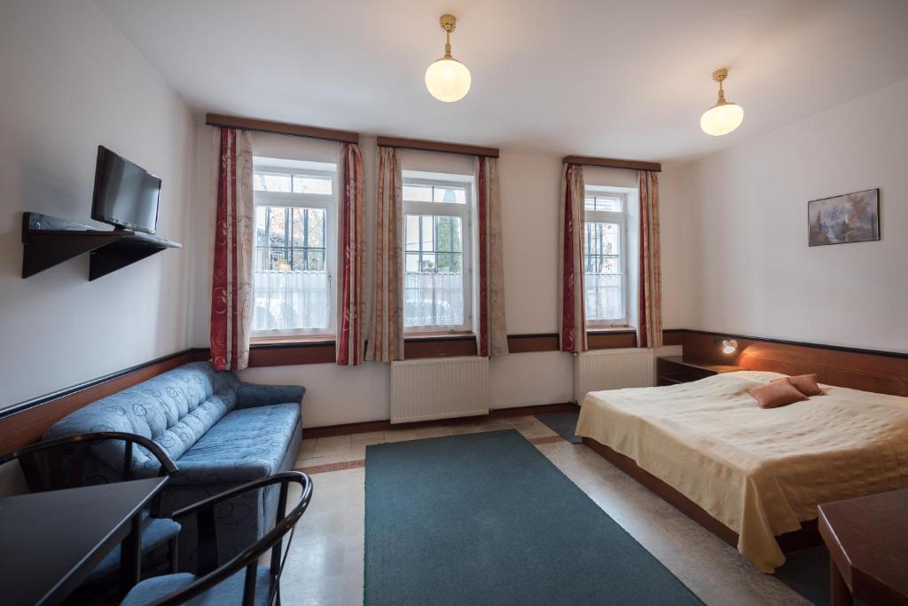 a bedroom with a bed and a couch and windows at Abbázia Club Hotel Kék in Keszthely