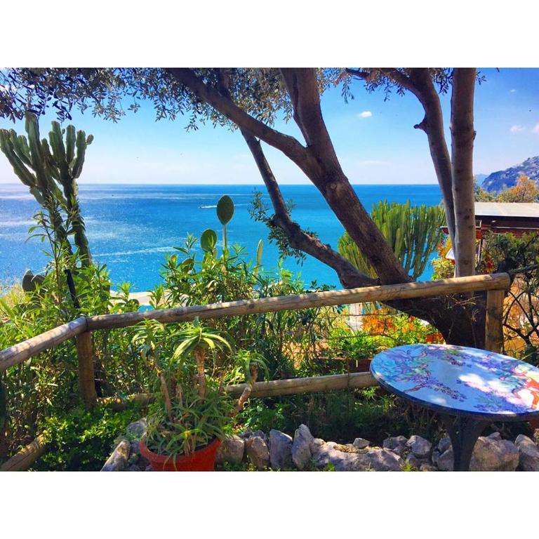 a view of the ocean from a garden with a table at Albergo La Conca Azzurra in Conca dei Marini