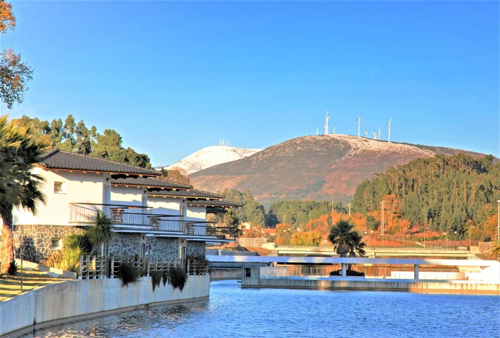 a bridge over a river with a mountain in the background at Praia das Rocas Bungalows in Castanheira de Pêra