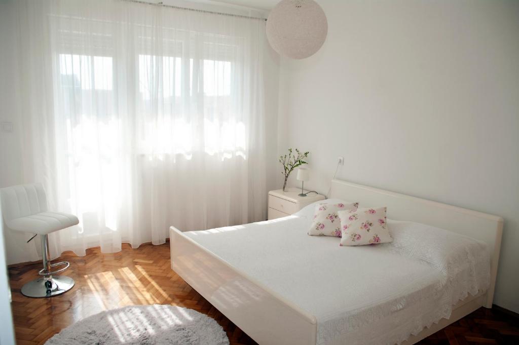 Dormitorio blanco con cama blanca y almohadas rosas en Apartment Sibenik with free parking, en Šibenik