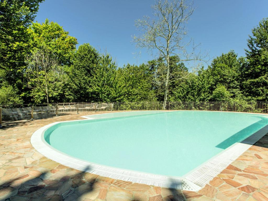 a large swimming pool in a yard with trees at Belvilla by OYO Cozy Holiday Home with barbecue in Polpenazze del Garda