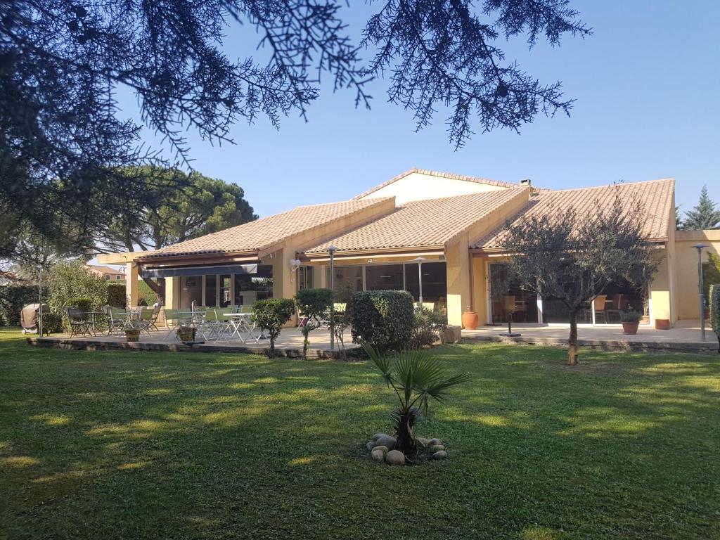 une maison avec un palmier dans la cour dans l'établissement Logis Hôtel Restaurant Le Mas De L'Olivier, à Pont-Saint-Esprit