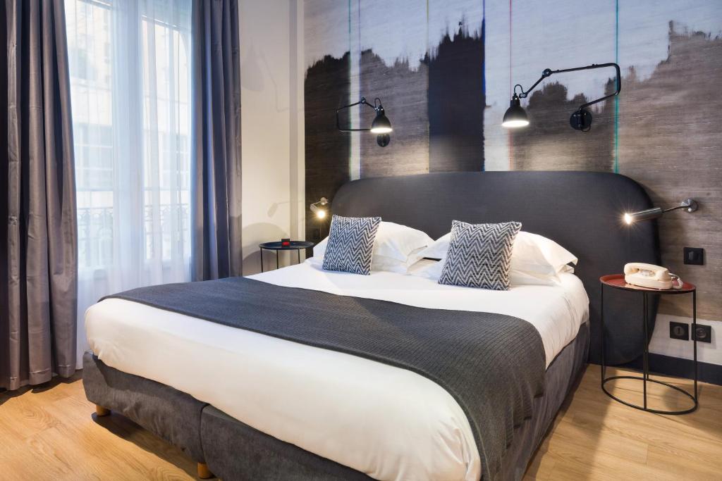a bedroom with a large bed with a black headboard at Hotel So’Co by Happyculture in Nice