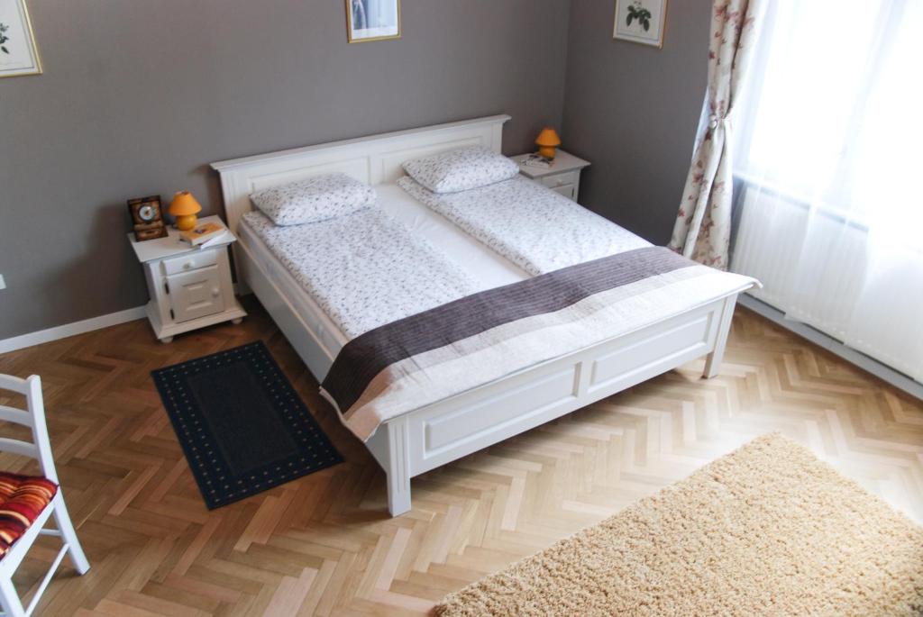ティミショアラにあるApartment House Timisoaraのウッドフロアのベッドルーム1室(白いベッド1台付)