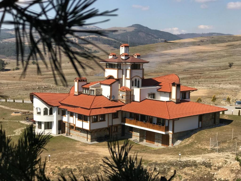 una grande casa con un tetto rosso su una collina di Park Hotel Eagle Stone a Koprivshtitsa