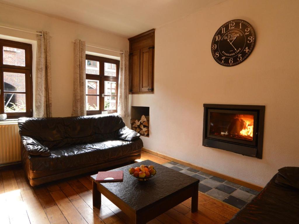 a living room with a couch and a clock on the wall at Spacious holiday home in Teuven with garden in Teuven