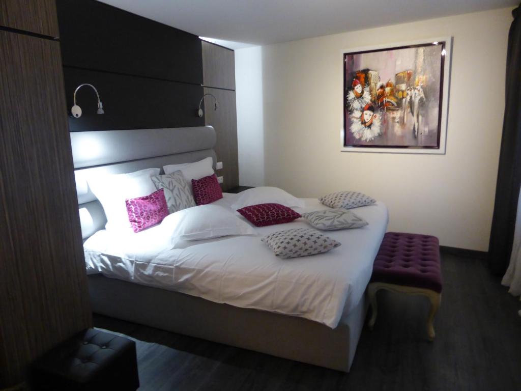 um quarto com uma cama grande e almofadas cor-de-rosa em L'Hostellerie du Château em Eguisheim