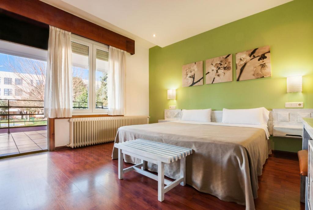 a green bedroom with two beds and a window at Hotel Los Olivos in Getafe