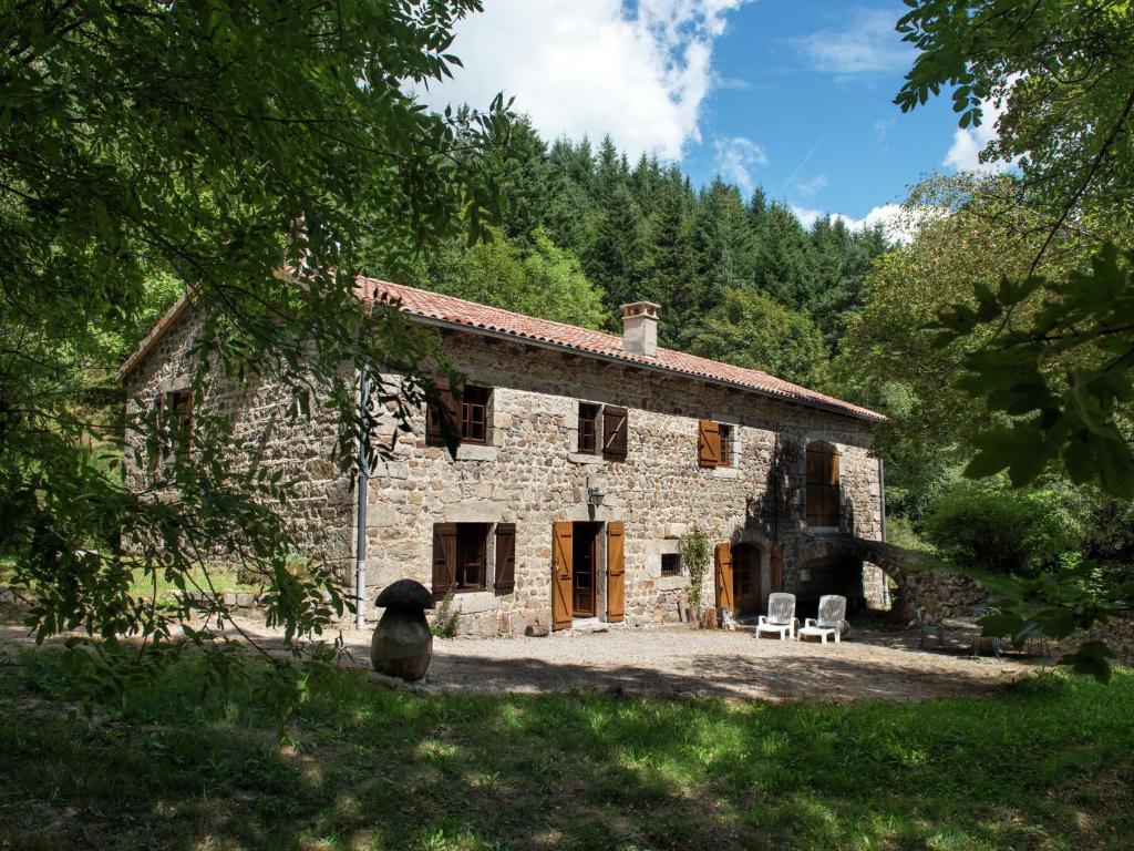 une ancienne maison en pierre avec deux chaises devant elle dans l'établissement Beautiful farmhouse in mountain forest setting, à Saint-Bonnet-le-Froid