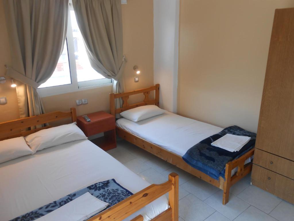 2 Betten in einem kleinen Zimmer mit Fenster in der Unterkunft Hotel Germany in Paralia Katerinis