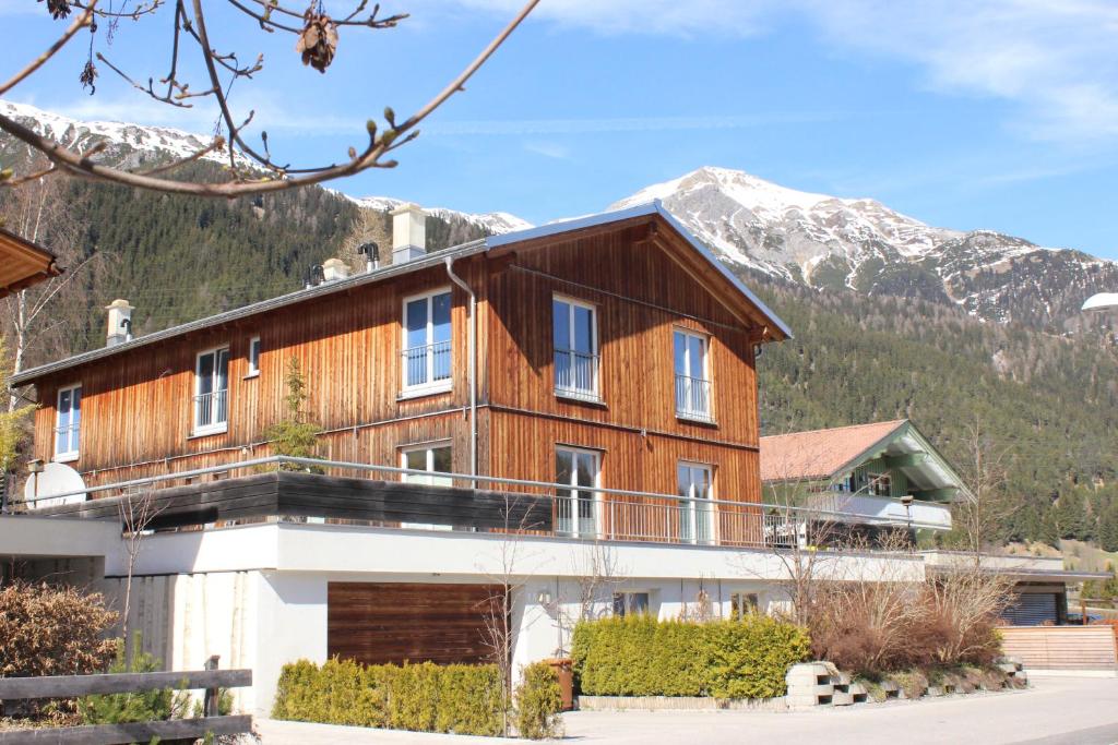 a large wooden house with mountains in the background at Ibex Lodge in Sankt Anton am Arlberg