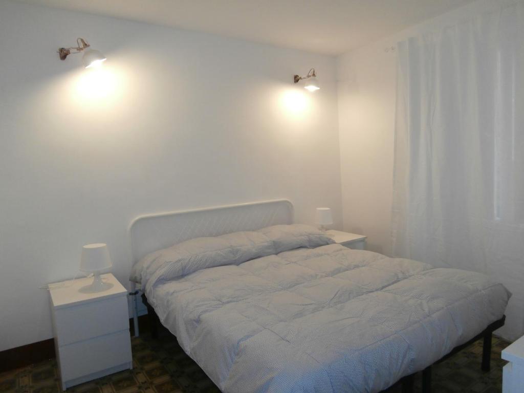 a white bedroom with a bed and two night stands at La Piccola Giudecca in Trapani