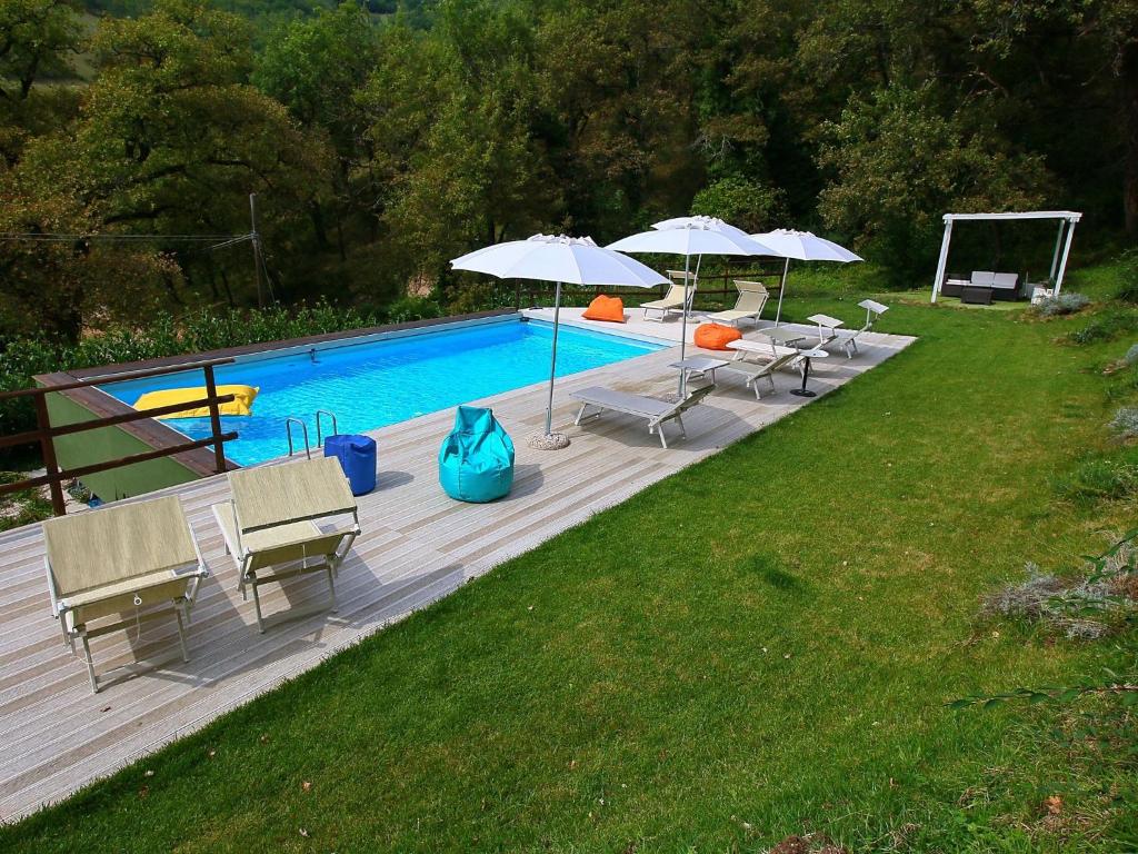 ファブリアーノにあるCozy Villa in Fabriano Italy with Swimming Poolの木製デッキのプール(椅子、パラソル付)