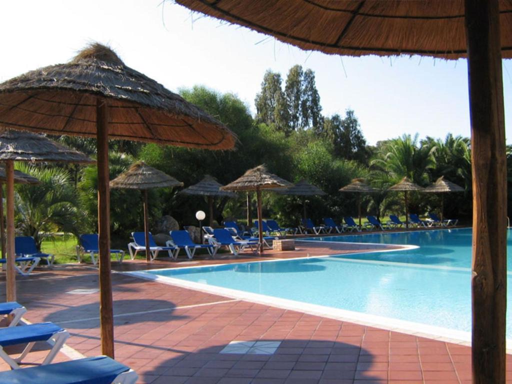 プーラにあるSpacious Holiday Home in Sardinia with Swimming Poolのパラソルと椅子付きのスイミングプール、スイミングプール