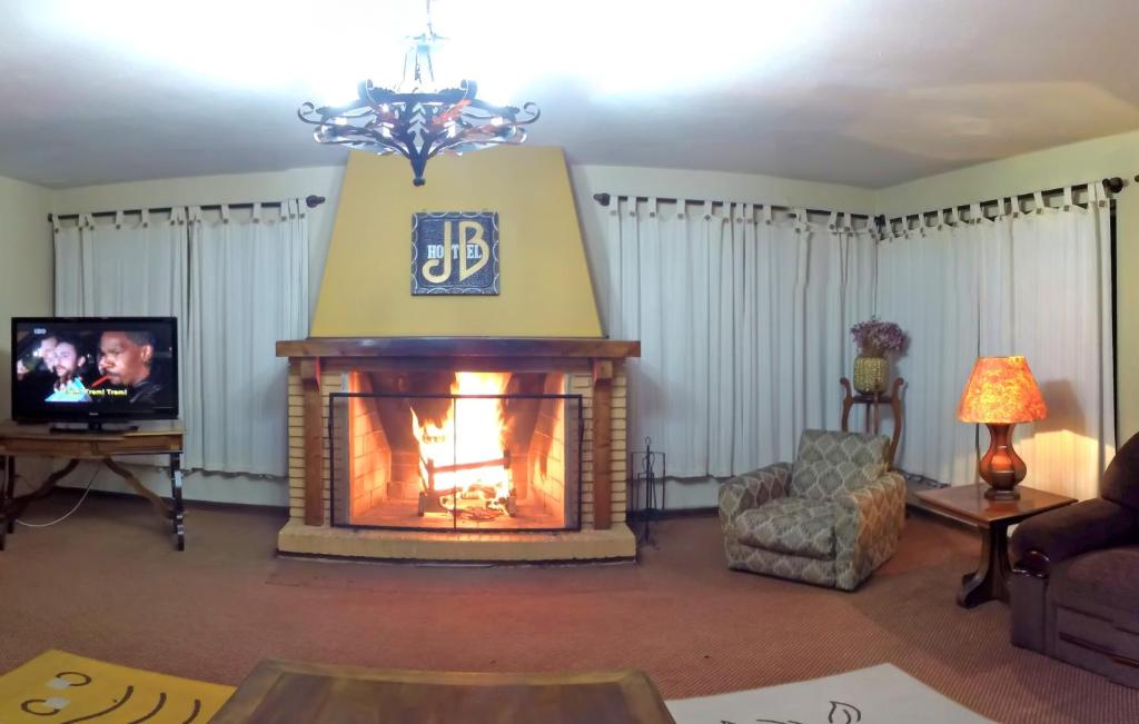 uma sala de estar com lareira e televisão em Hotel JB em Campos de Jordão