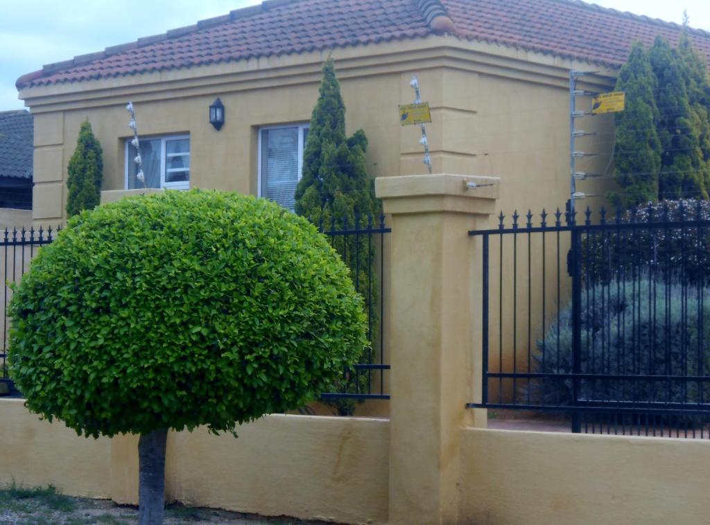 una casa con un cancello e un cespuglio davanti di Toscana Cottage a Port Elizabeth