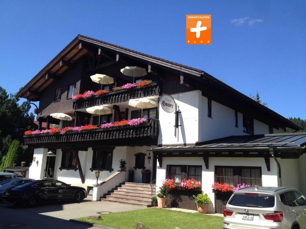 ein großes weißes Gebäude mit Blumen auf dem Balkon in der Unterkunft Kur- und Ferienhotel Haser in Oberstaufen