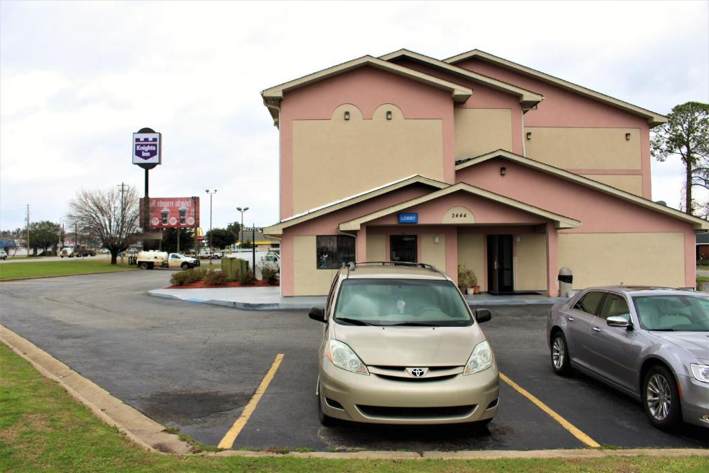 dos autos estacionados en un estacionamiento frente a una tienda en Knights Inn Albany en Albany